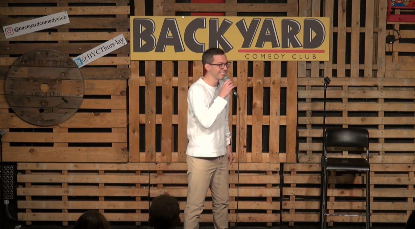 An image of Adam Phillips doing standup in the backyard comedy club.